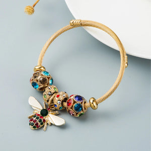 Gold bracelet with colorful beads and a bee charm 