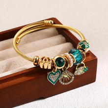 Load image into Gallery viewer, Gold bracelet with charms on a wooden display box